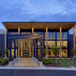 The Lodge at Autumn Willow entrance at dusk, with a glowing timber canopy and glass facade.