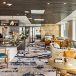 Sophisticated sky lounge at The Watermark at Bellevue independent living tower in Bellevue, Washington, featuring a marble bar, modern seating, a linear fireplace, and large windows with scenic views.